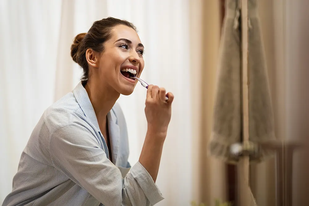 happy woman cleaning her teeth with toothbrush morning